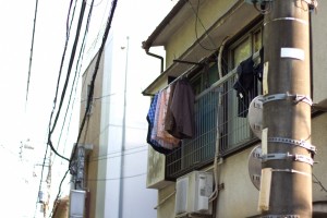 窓に洗濯物を干しているアパートの一室を通りから見たところ
